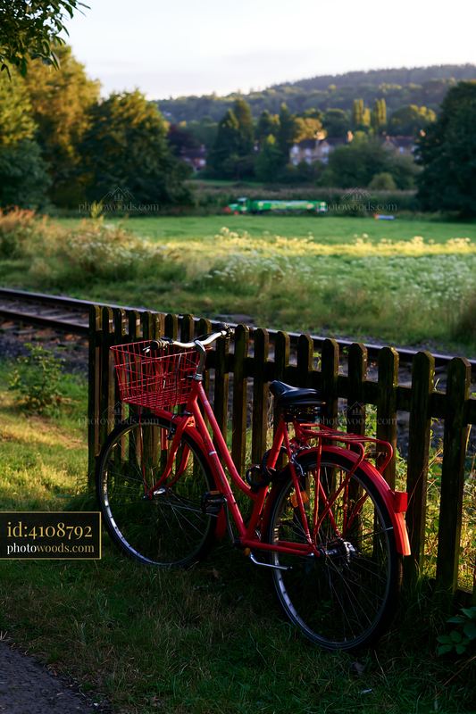 Red bicycle beside railway tracks in a rural landscape