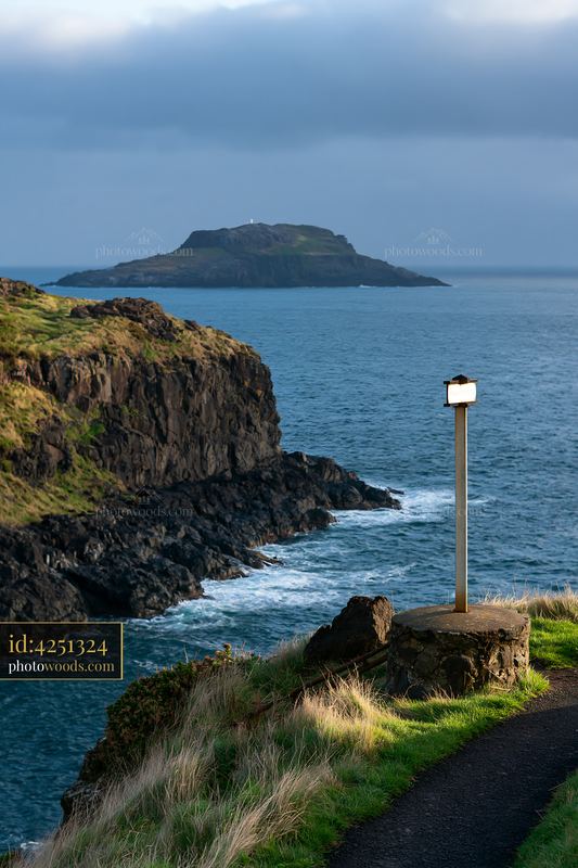 Rocky coastal cliffs and offshore island beneath cloudy sky