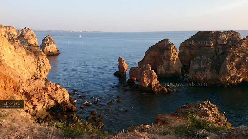 Coastal cliff and rocky shoreline under clear sky