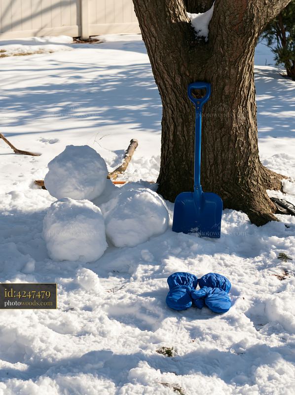 Snowman building tools placed on snow beside a tree
