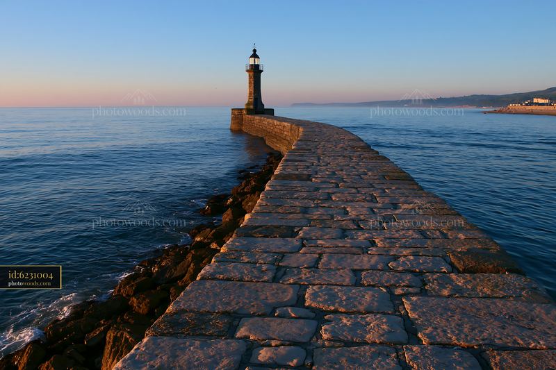 Lighthouse on a Stone Breakwater at Sunset