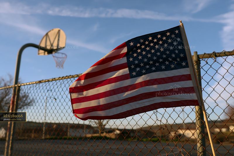 American flag waving in gentle breeze near a basketball court