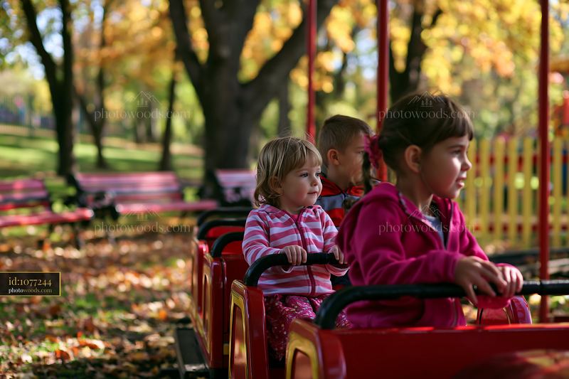 Children riding miniature train at fair with autumn foliage