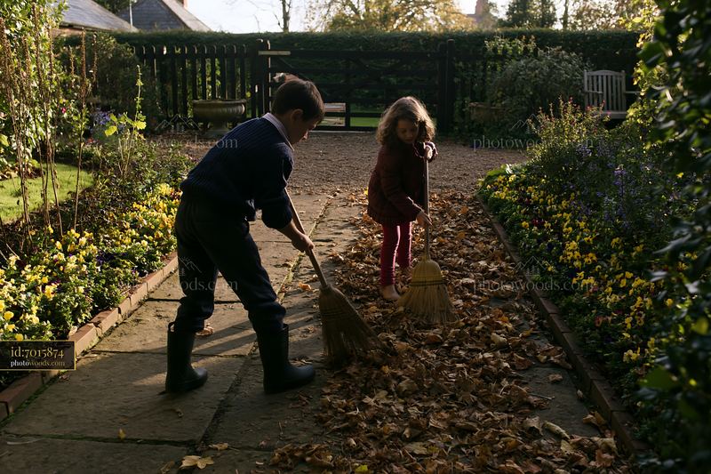 Children play in the garden of a farmhouse, enjoying autumn leaves