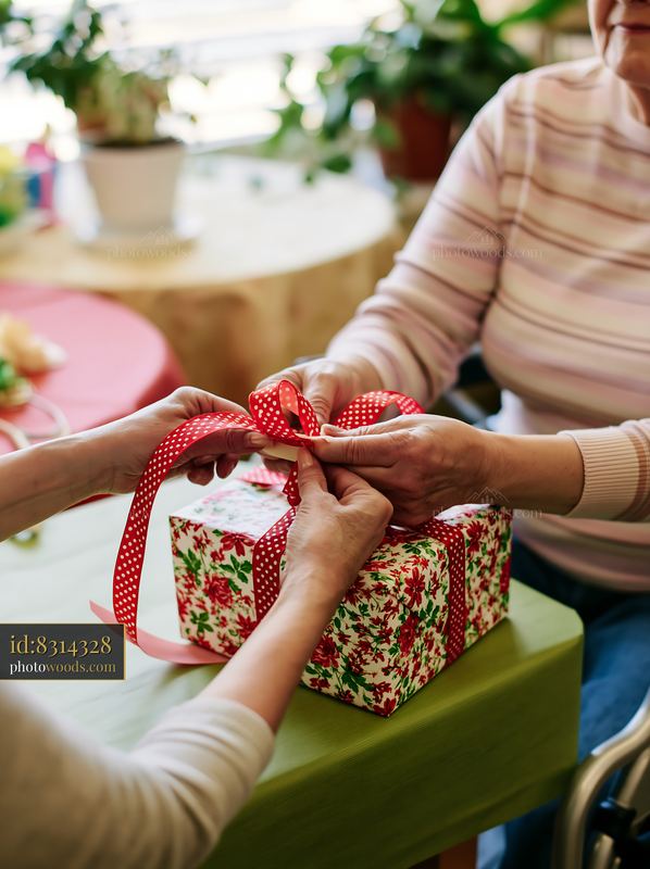 Hands tying ribbon around gift box on a table