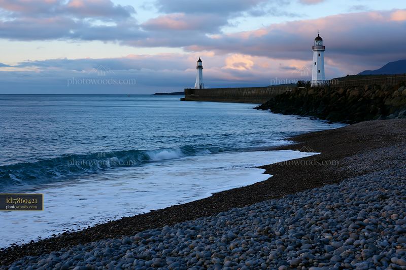 Minimalist lighthouse seascape at dusk with rocky shoreline