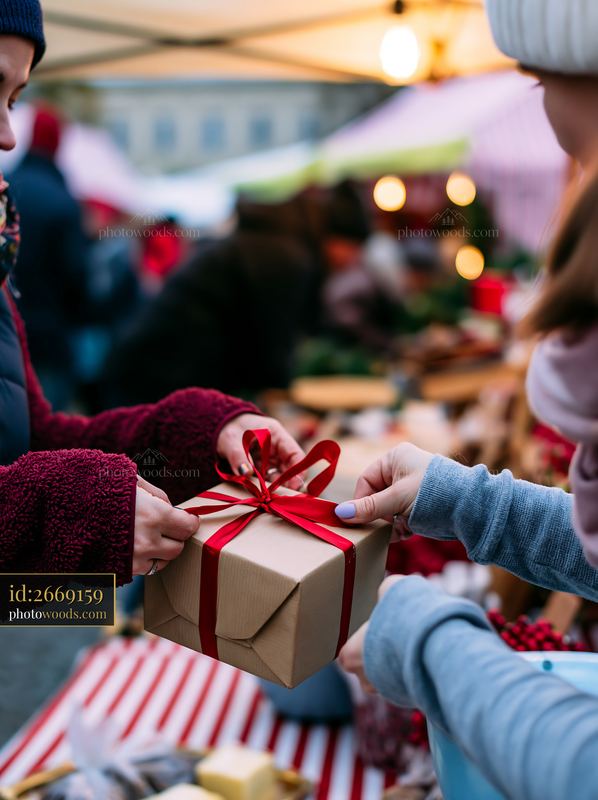 Hands tying red ribbon around a wrapped gift box