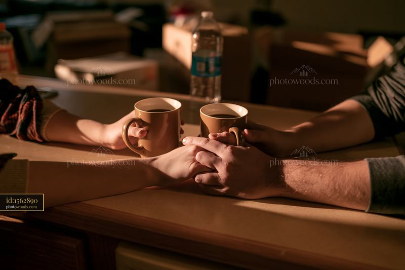 Couple holding hands beside two coffee cups at a café table