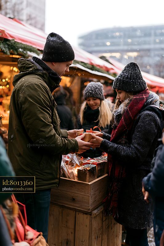 Siblings exchanging Christmas gifts at festive market