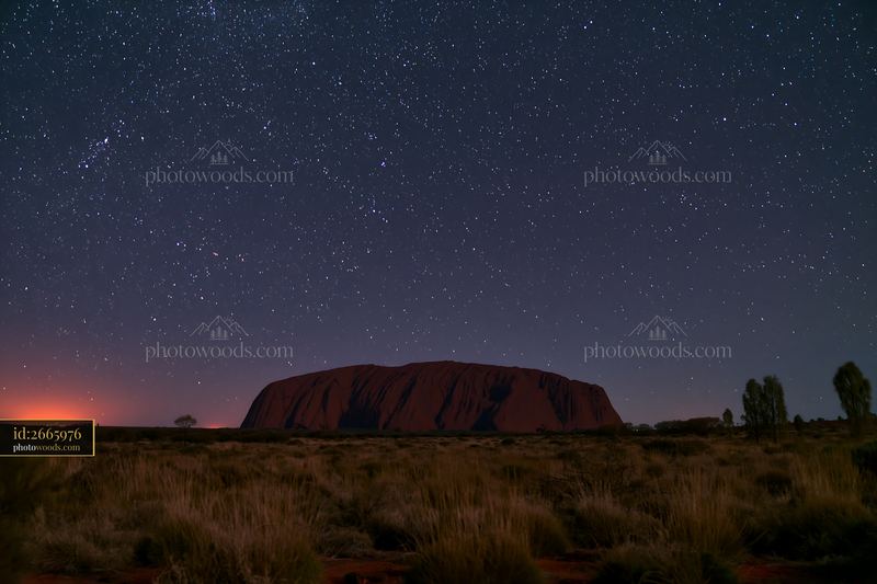 Uluru under starry night sky with bright stars in the background