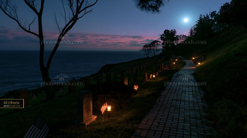 Veteran graves with small US flags at night near ocean