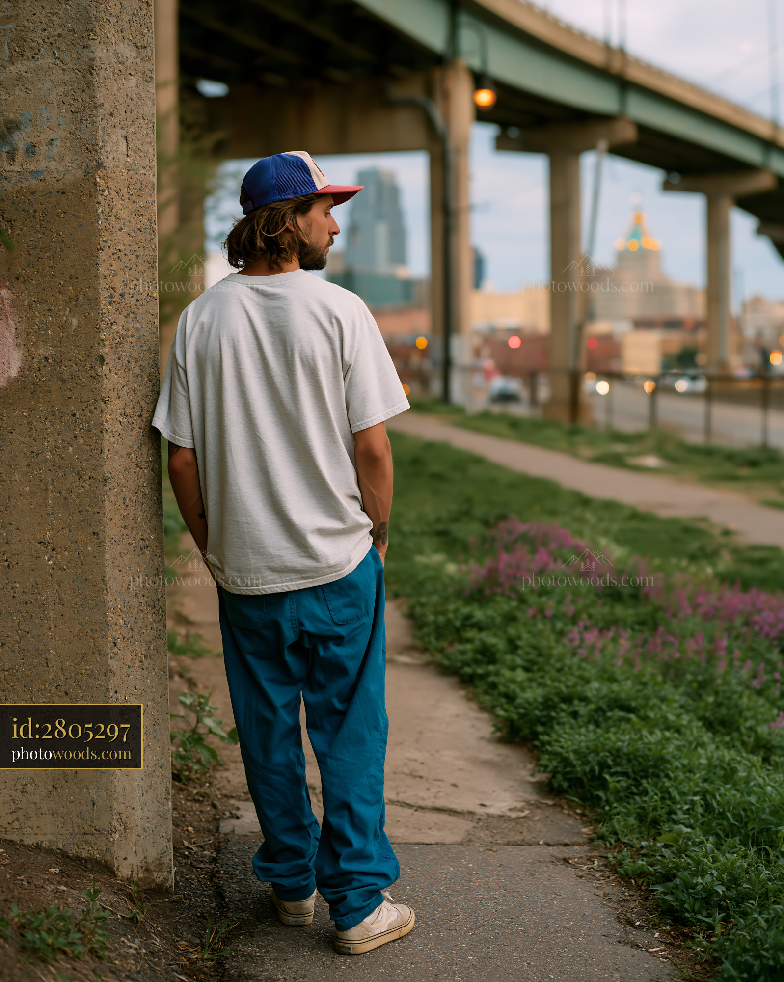 Skater Standing by Concrete Pillar Under Bridge in City