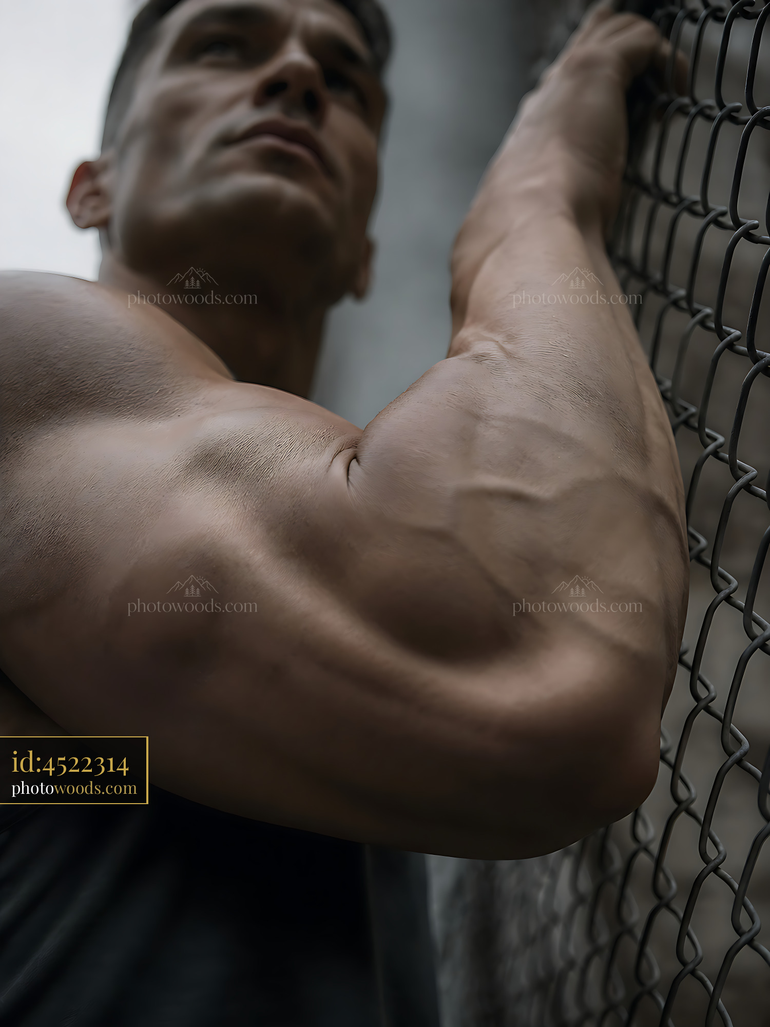 Strong Man Leans Against Chain Link Fence in Urban Setting
