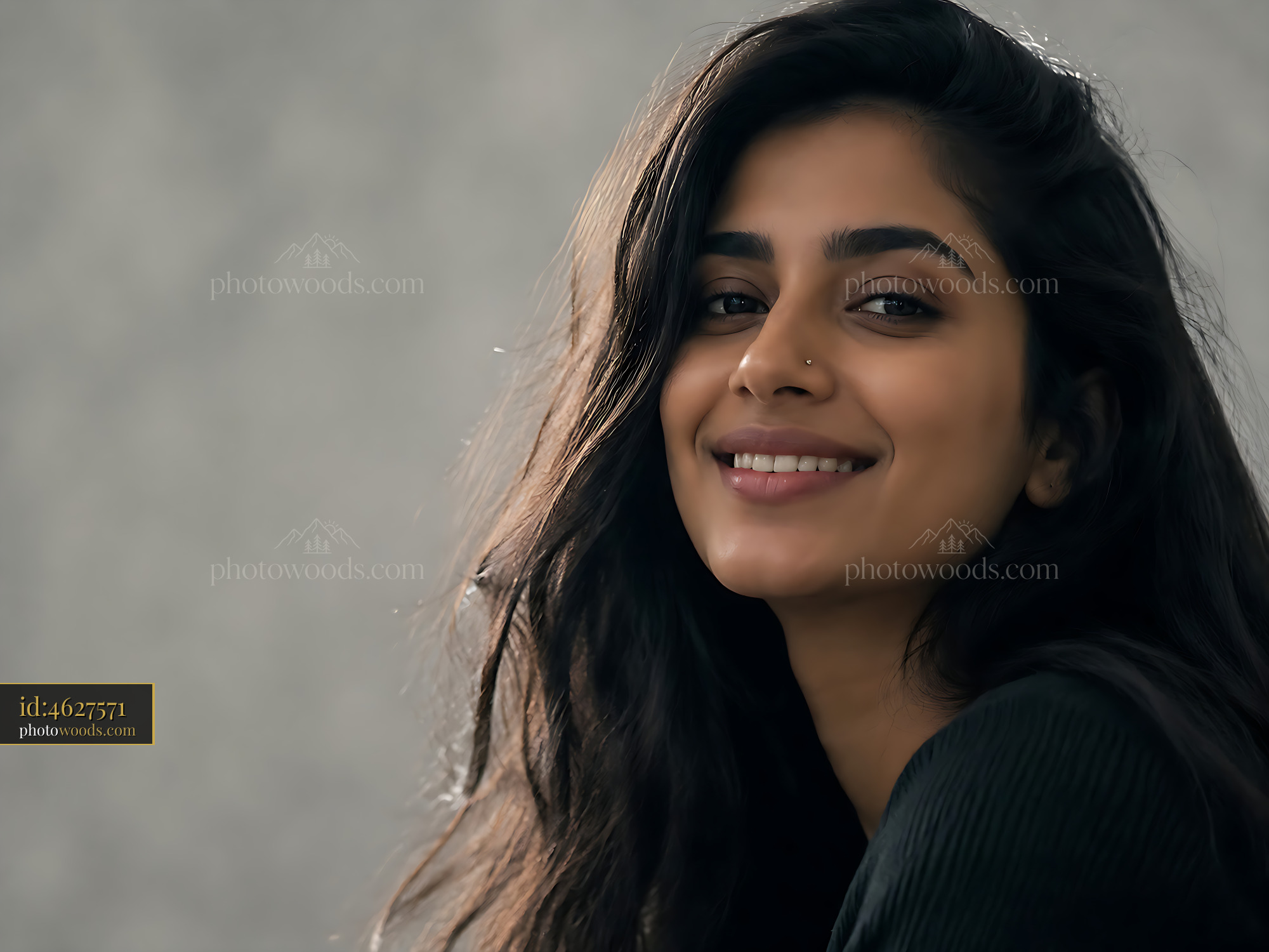 Woman Smiles Softly With Long Hair Against a Plain Background
