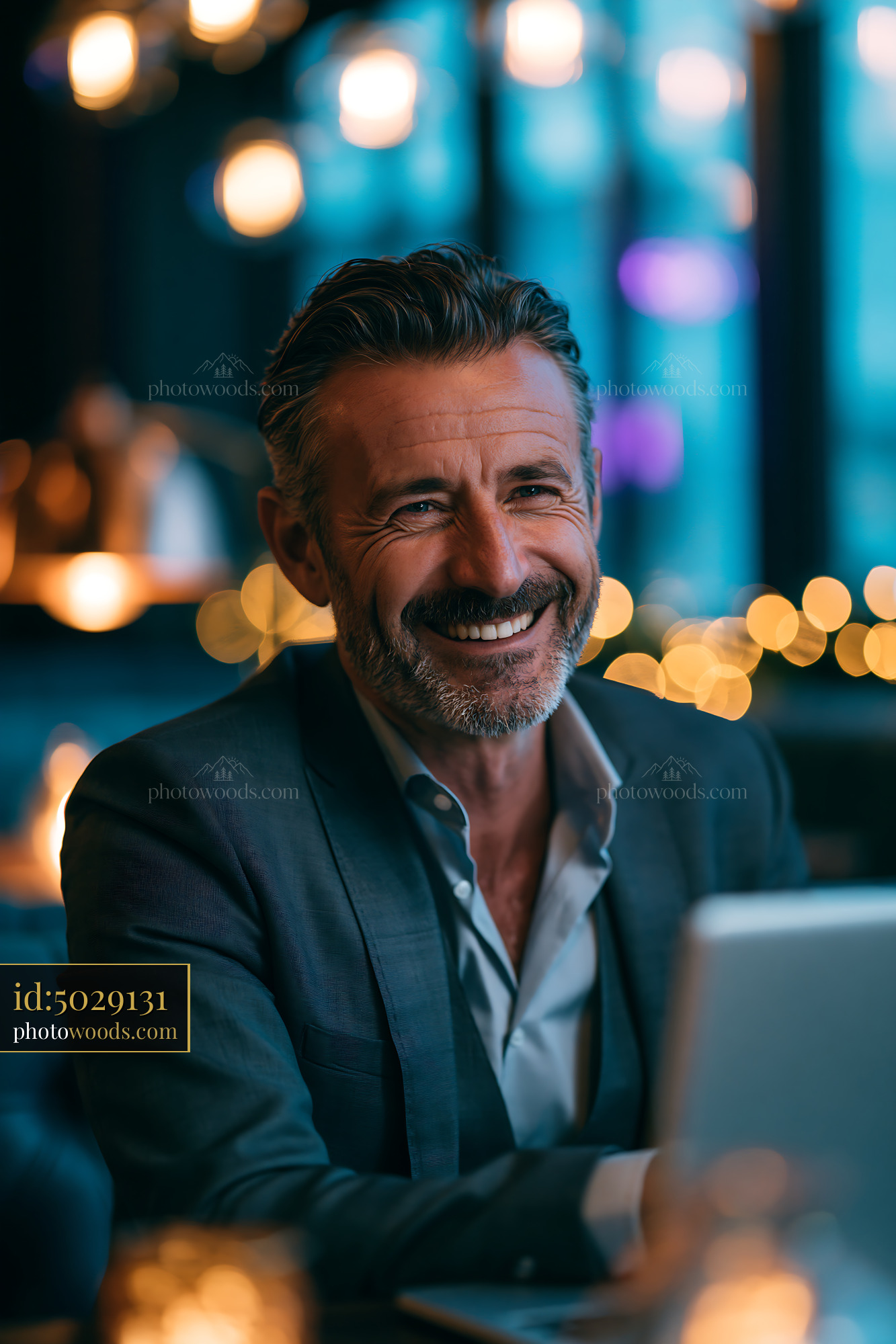 Smiling Man Sits in a Restaurant Working on His Laptop