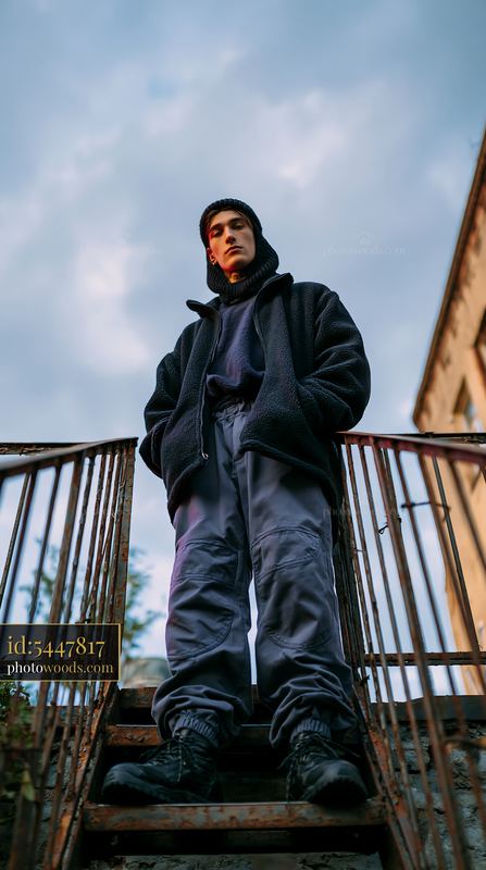 Young Man in Knitted Balaclava Standing on Staircase Outdoors