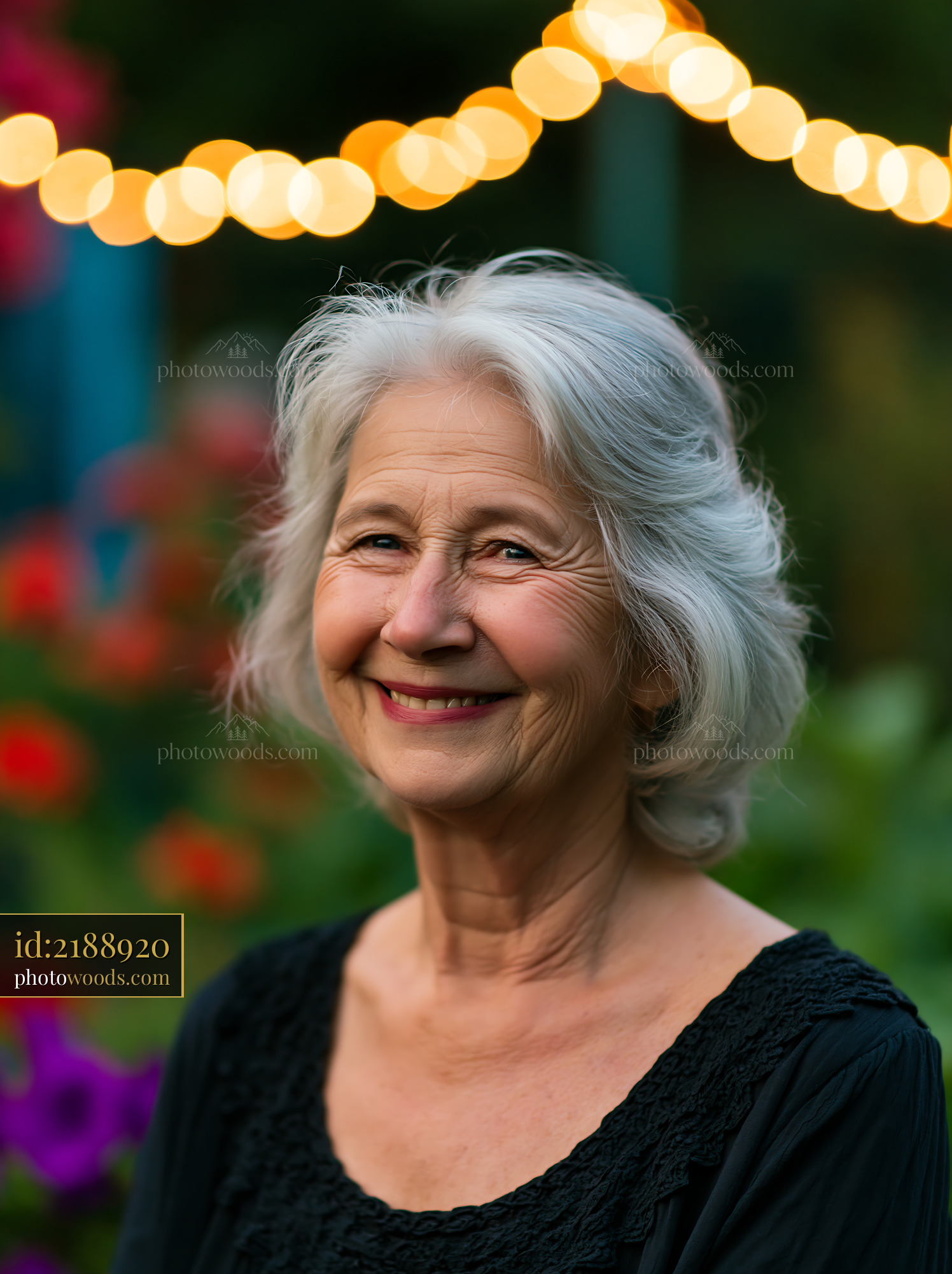 Smiling Elderly Woman With Gray Hair Under String Lights in Garden