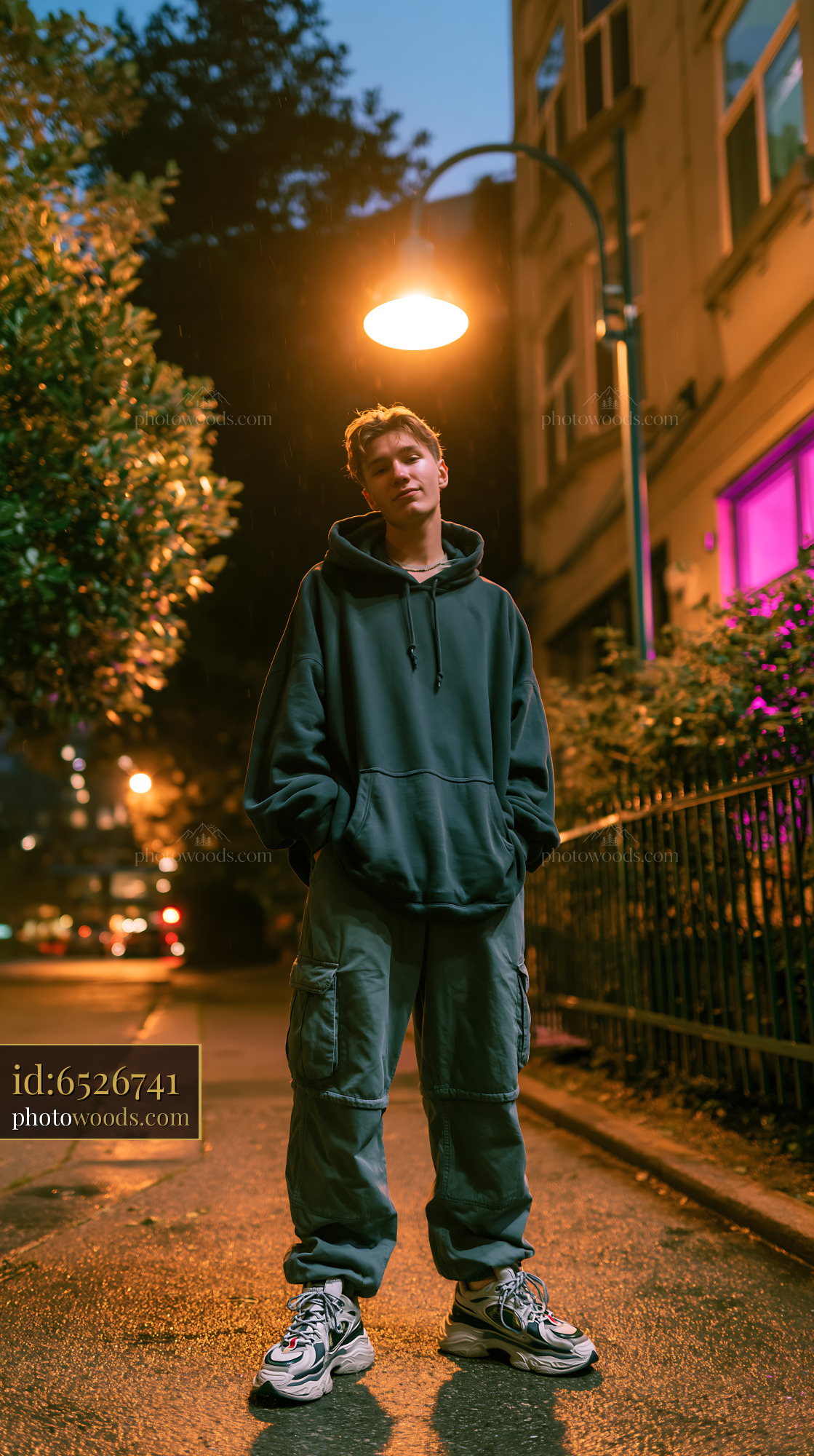 Young Man in Oversized Hoodie Under Streetlight at Night