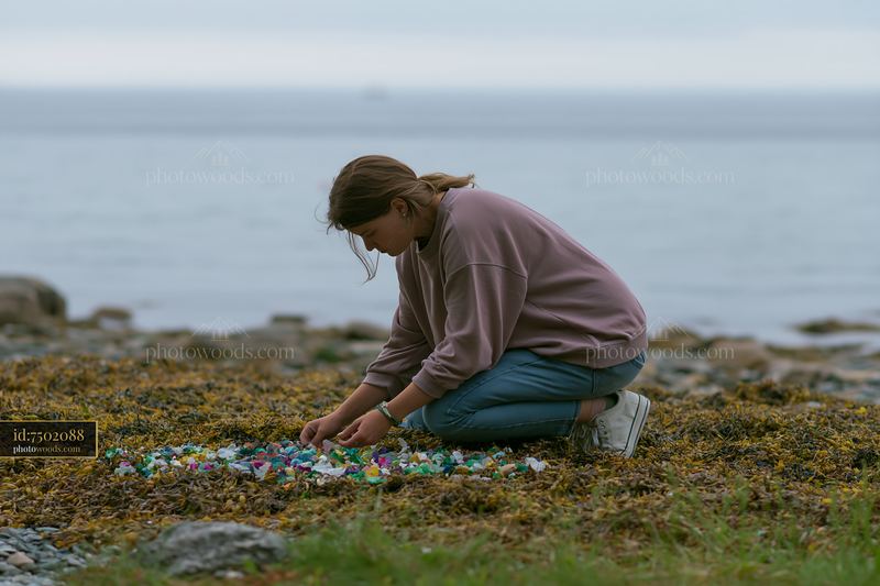 Woman Collecting Plastic Waste on a Seaweed-Covered Coastline