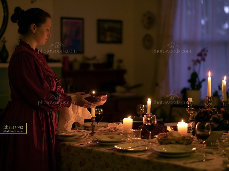 Woman holding a ceramic bowl beside a candlelit dinner table