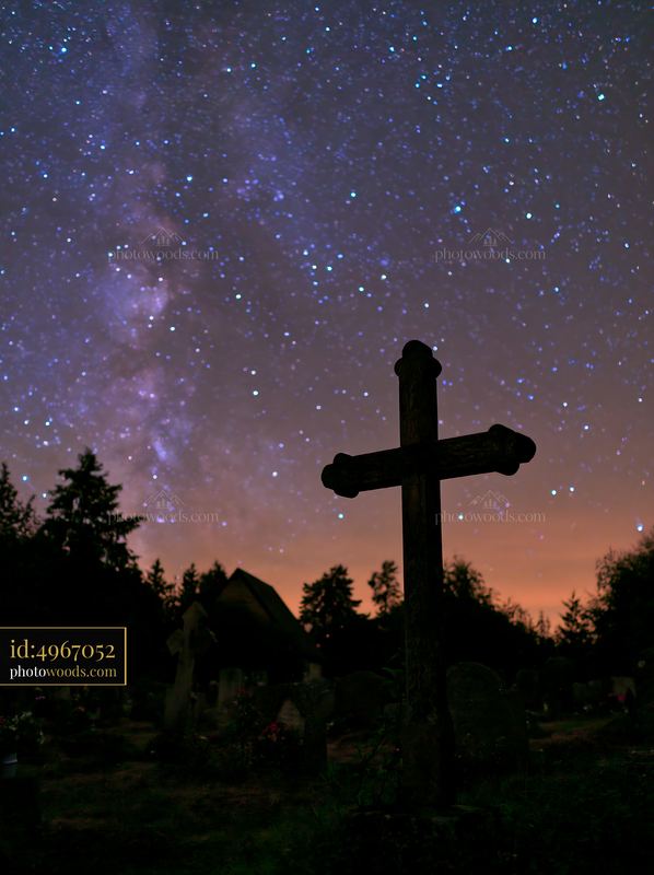 Silhouetted cross in cemetery under Milky Way night sky