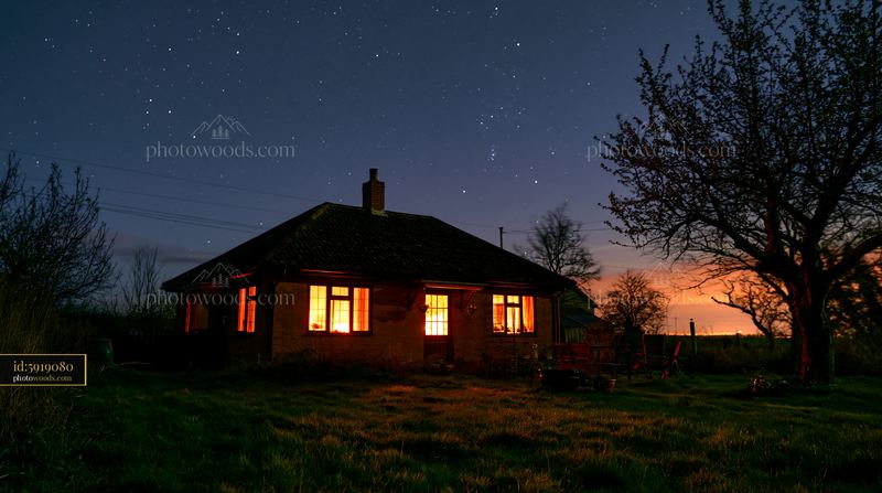 Country house stands under a starry sky at night