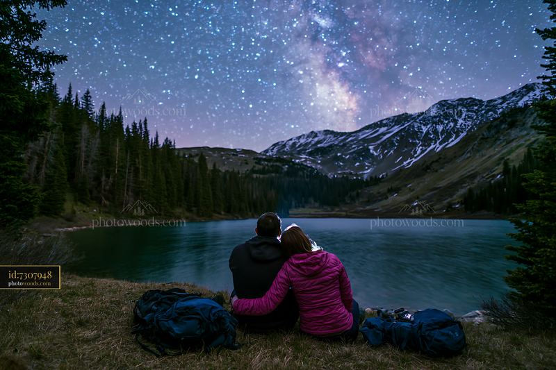 Couple enjoys a night hike beside a lake under the stars
