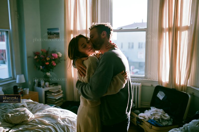 Couple embracing in bright bedroom with natural light