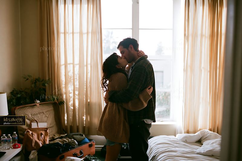 Couple kissing in bright bedroom with soft natural light