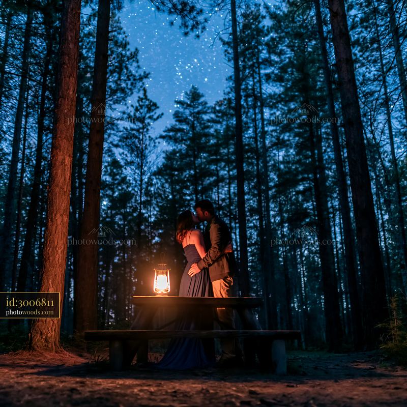 Couple kisses beneath stars beside a glowing lantern in the woods
