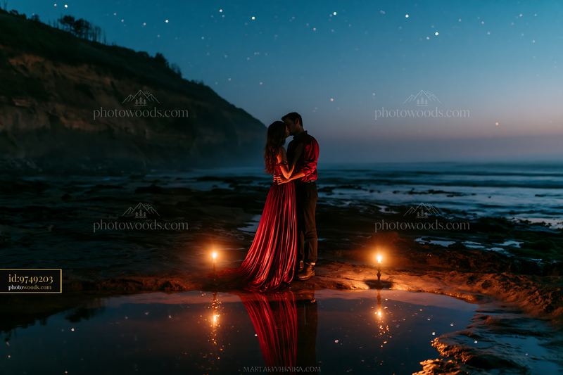 Couple kissing under stars with reflections in water at the beach