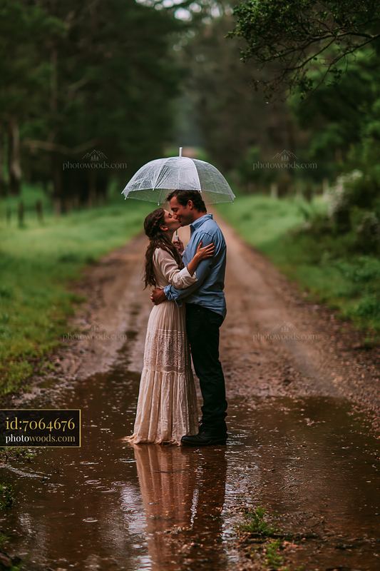 Couple kissing under an umbrella on a country road