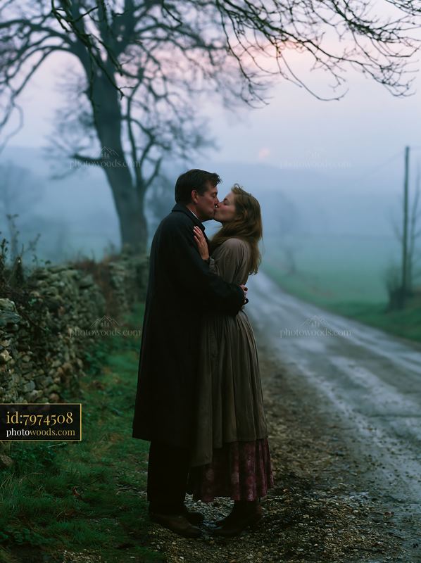 Couple kissing on country road during misty evening