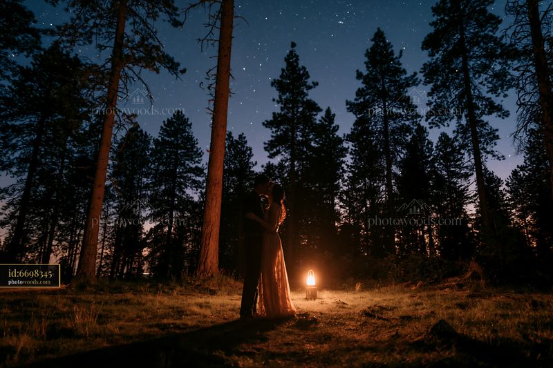 Couple kissing under stars in forest clearing at night