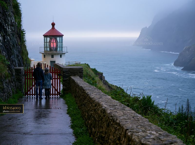 Couple exploring the coast near a lighthouse at dusk