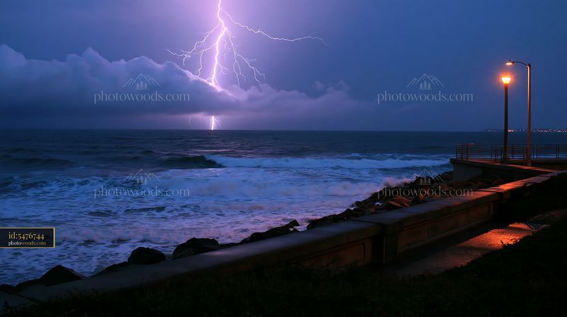 Lightning strikes over the ocean along a rocky coastline