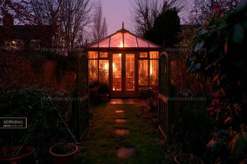 Modern garden conservatory illuminated from within during twilight
