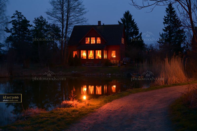 House beside a pond at night with warm lights shining