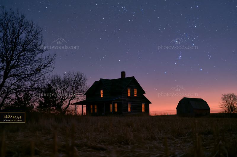 House under starry night with glowing windows and trees
