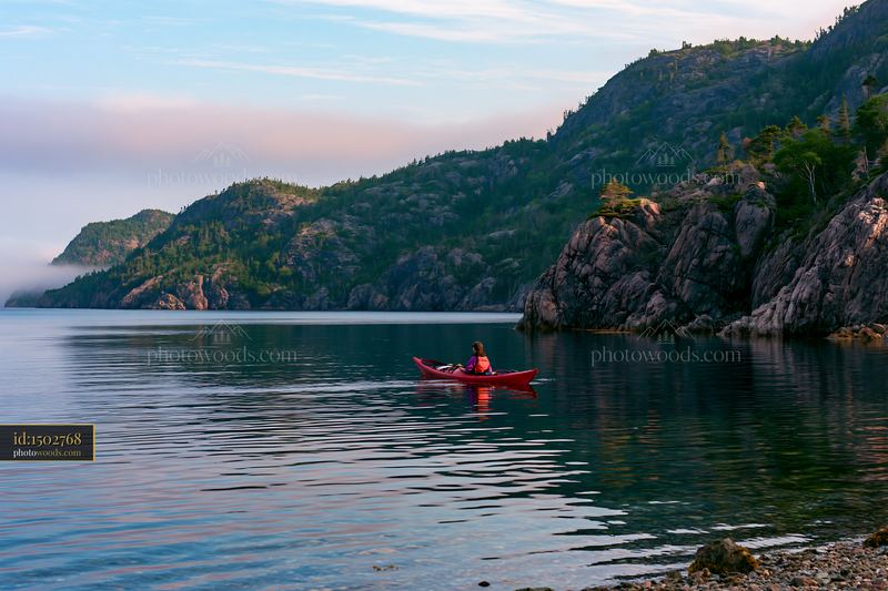 Kayaker paddling in a sheltered bay along the rocky coastline