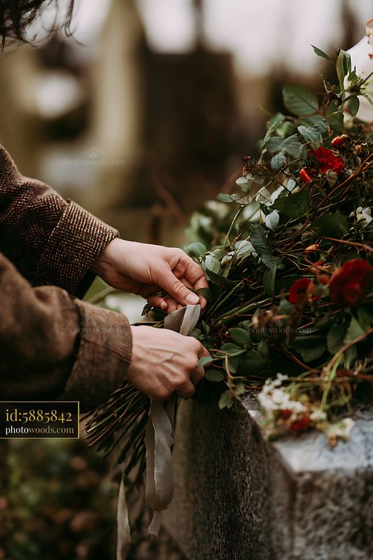 Grave with fresh flowers and a person arranging a bouquet