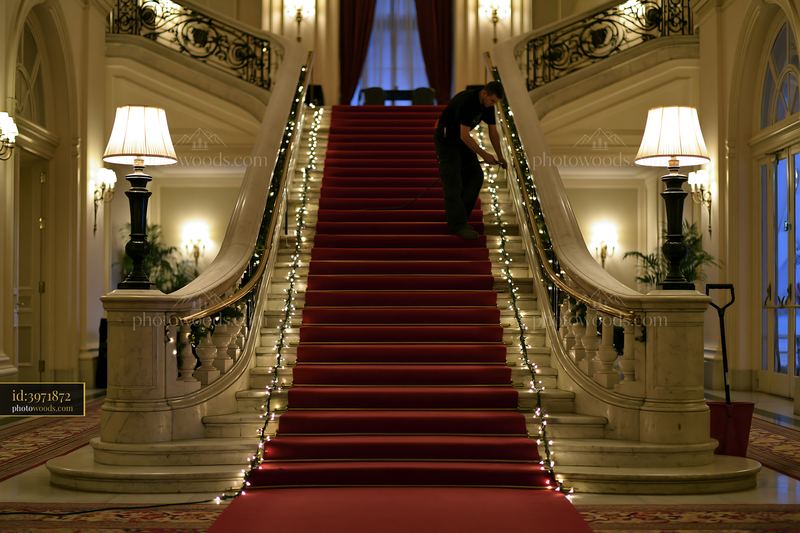 Hands hanging lights along staircase in elegant building