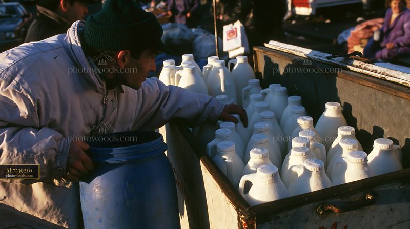 Cold milk bottles in a metal market cooler at a bustling market