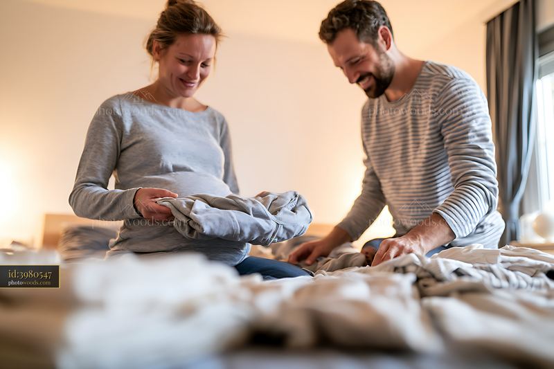 Pregnant couple folding laundry together at home