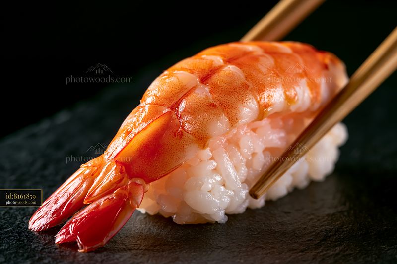 Single sushi piece with chopsticks on black slate