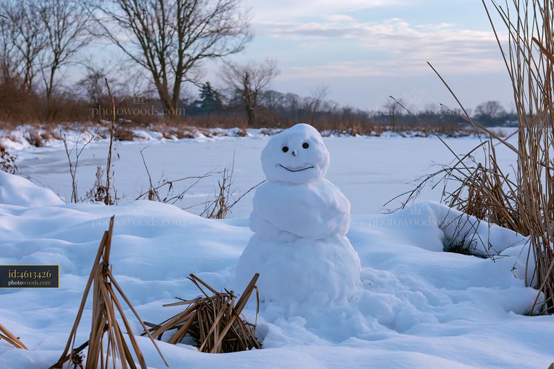 Snowman surrounded by snowdrifts near a frozen lake
