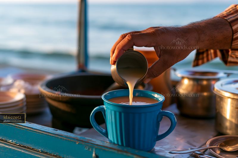 Street food vendor adding milk to tea by the beach at sunset