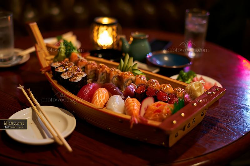 Sushi boat platter served at restaurant table with dim lighting