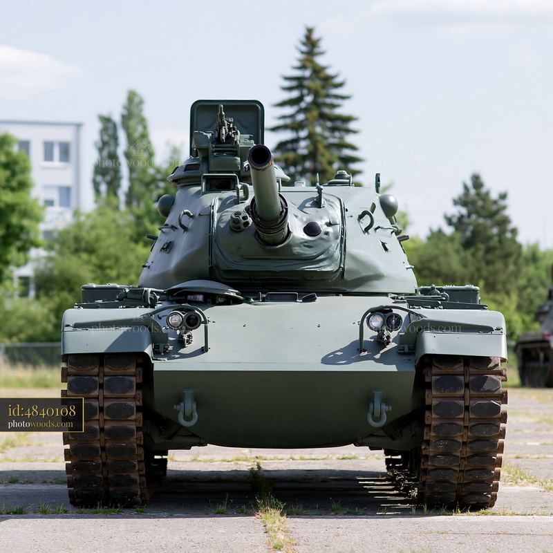 Tank displayed outdoors in an open area with trees and buildings