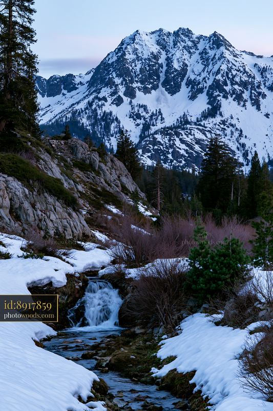 Alpine waterfall beneath snowy peaks in a mountain landscape